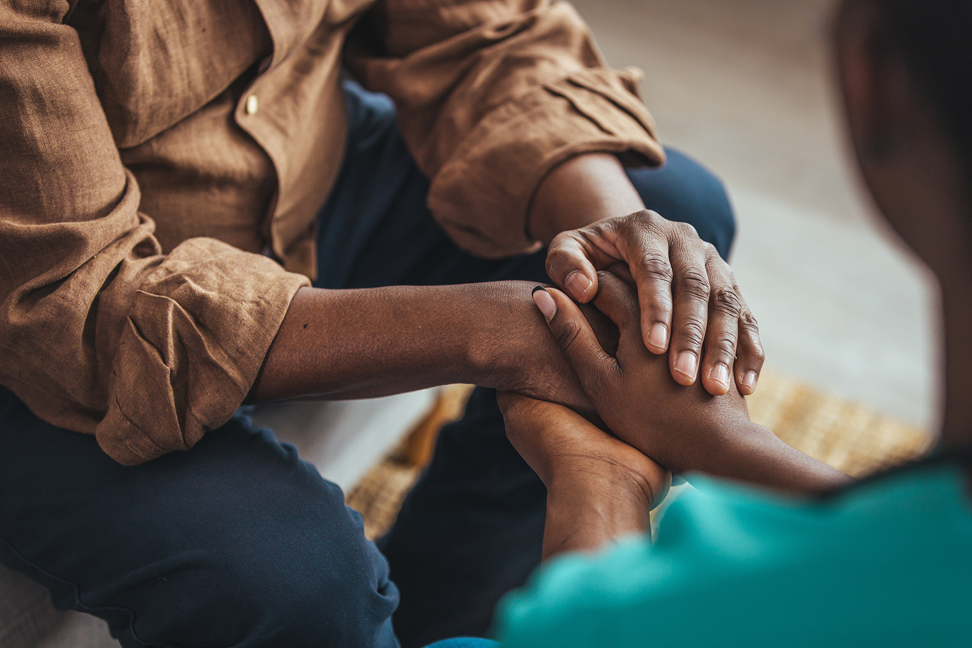 A close up shot of a young woman holding a senior man's hands in comfort